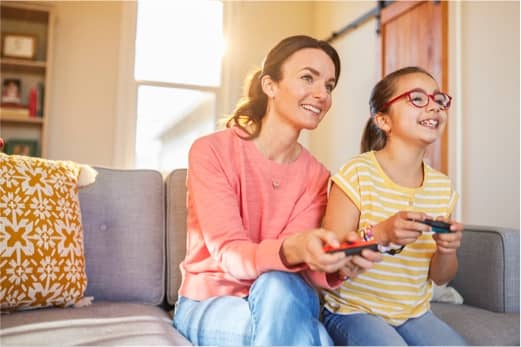 Two people are on a sofa playing Big Brain Academy: Brain vs. Brain on a Nintendo Switch system.